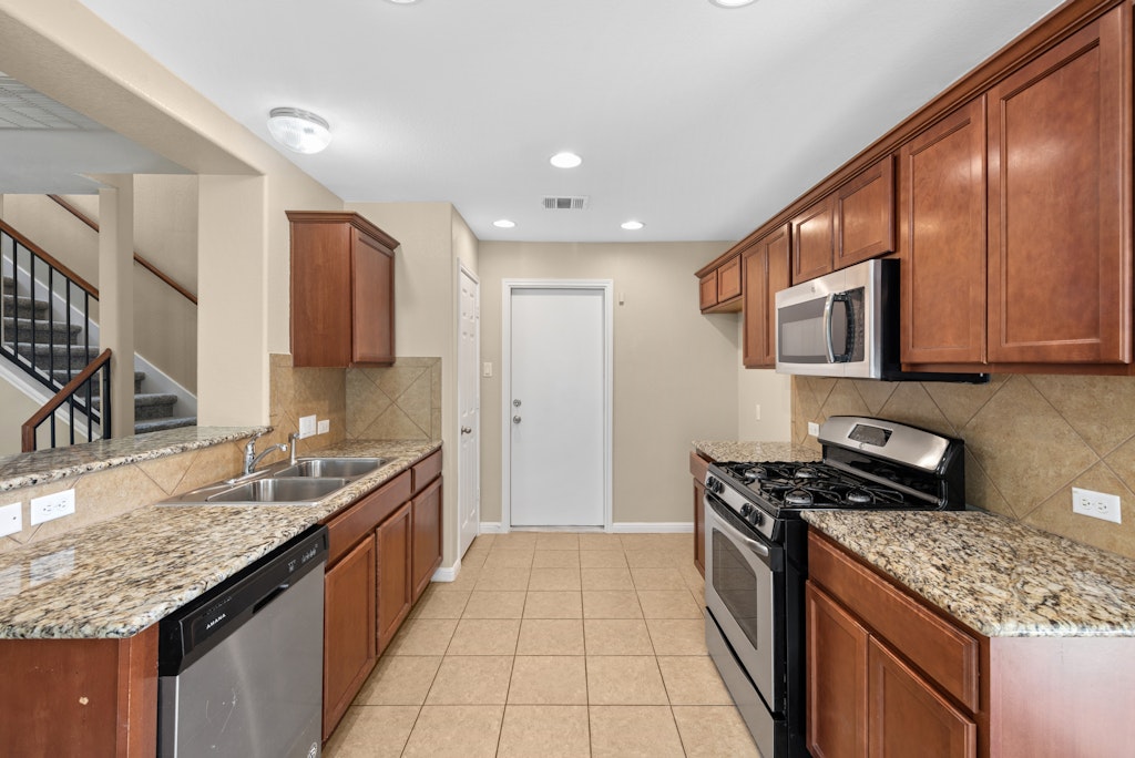458 Nottingham Loop Kyle, TX 78640 - Photo 7 of 38 a kitchen with stainless steel appliances granite countertop a sink and a stove