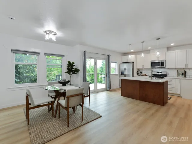 a kitchen with a table chairs wooden floor and a large window