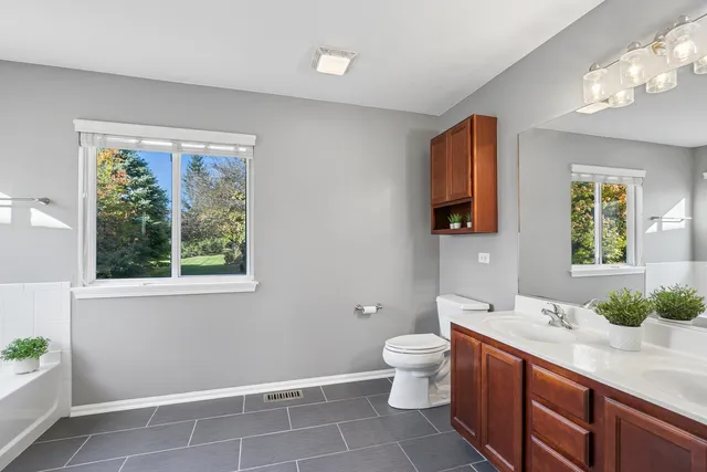 a spacious bathroom with a double vanity sink toilet and a mirror