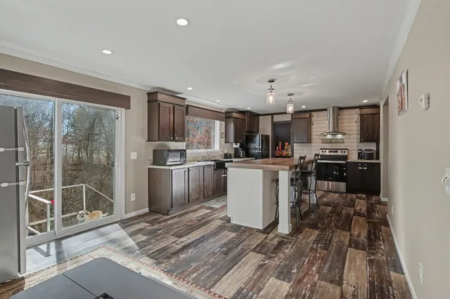 a open kitchen with kitchen island a sink a stove a refrigerator cabinets and a dining table