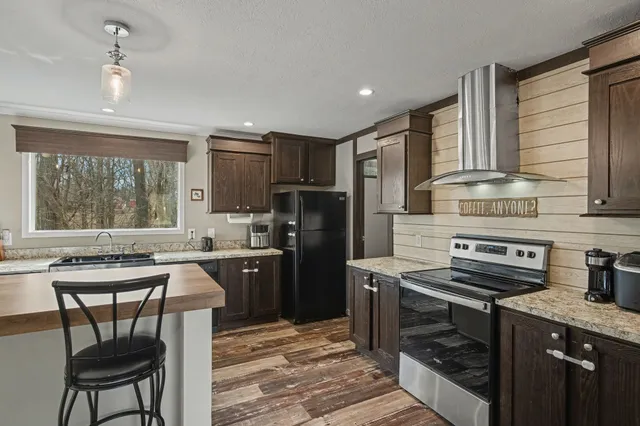 a kitchen with kitchen island granite countertop a stove refrigerator sink and cabinets