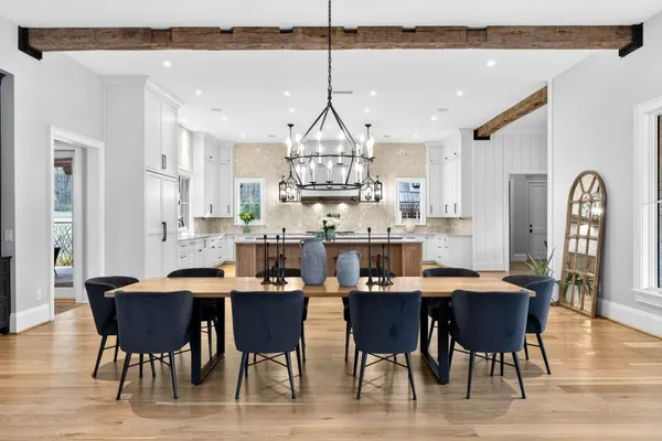 a large kitchen with kitchen island a stove a sink a dining table and chairs with wooden floor