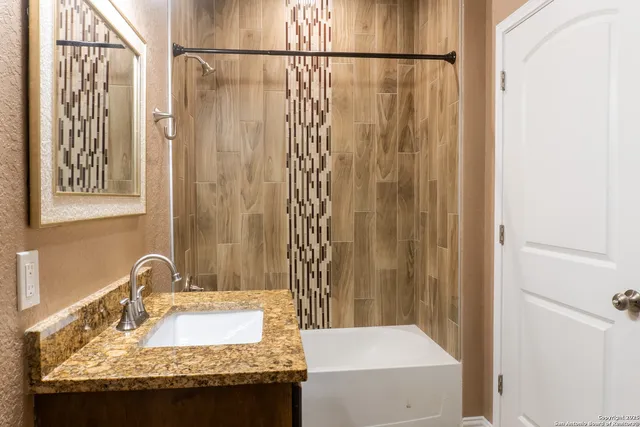 a bathroom with a granite countertop sink and a mirror