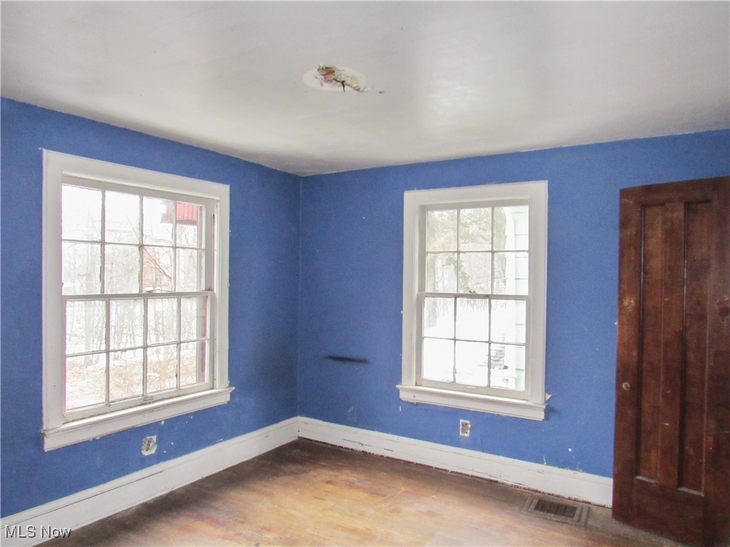 14450 Superior Road Cleveland, OH 44118 - Photo 14 of 35 Empty room with visible vents, plenty of natural light, wood finished floors, and baseboards