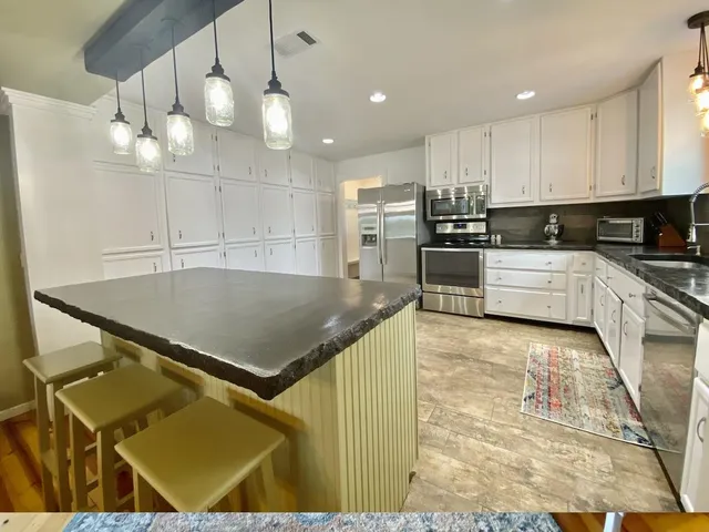 a kitchen with kitchen island a counter top space appliances and cabinets
