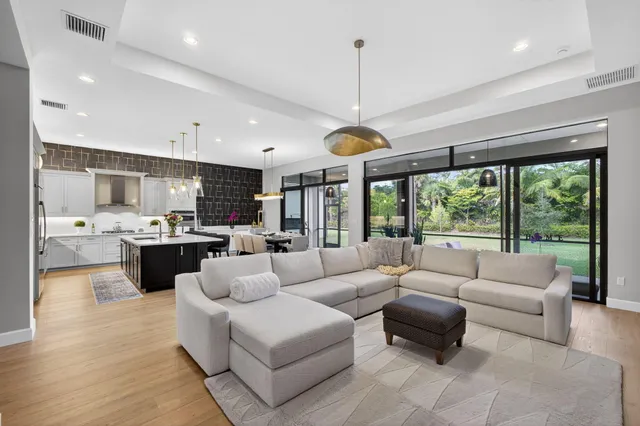 a living room with furniture kitchen area and a large window