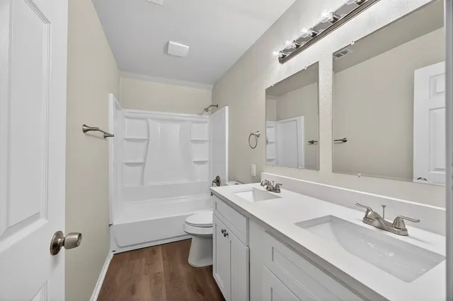 a bathroom with a double vanity sink toilet mirror and bathtub