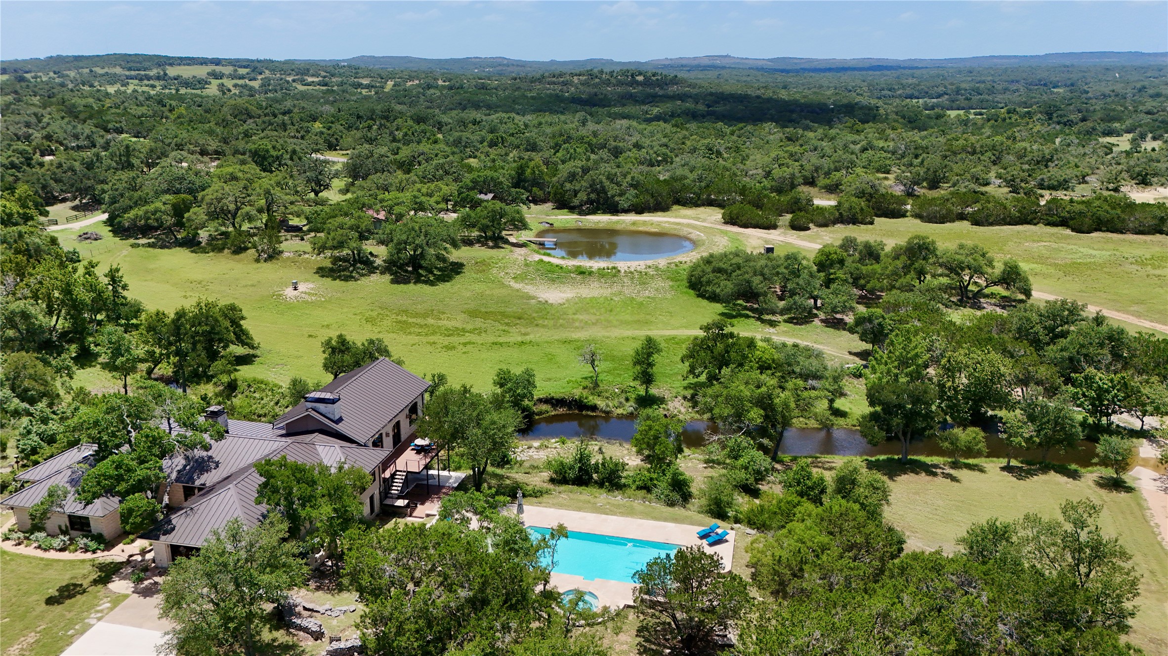 an aerial view of residential house with outdoor space and trees all around