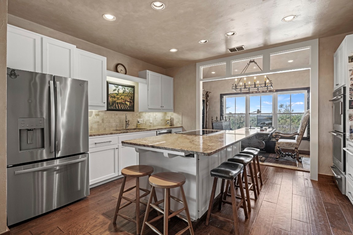 5801 Mount Gainor Road Wimberley, TX 78676 - Photo 14 of 40 Kitchen with stainless steel refrigerator with ice dispenser, recessed lighting, white cabinetry, dark wood finished floors, and a kitchen island