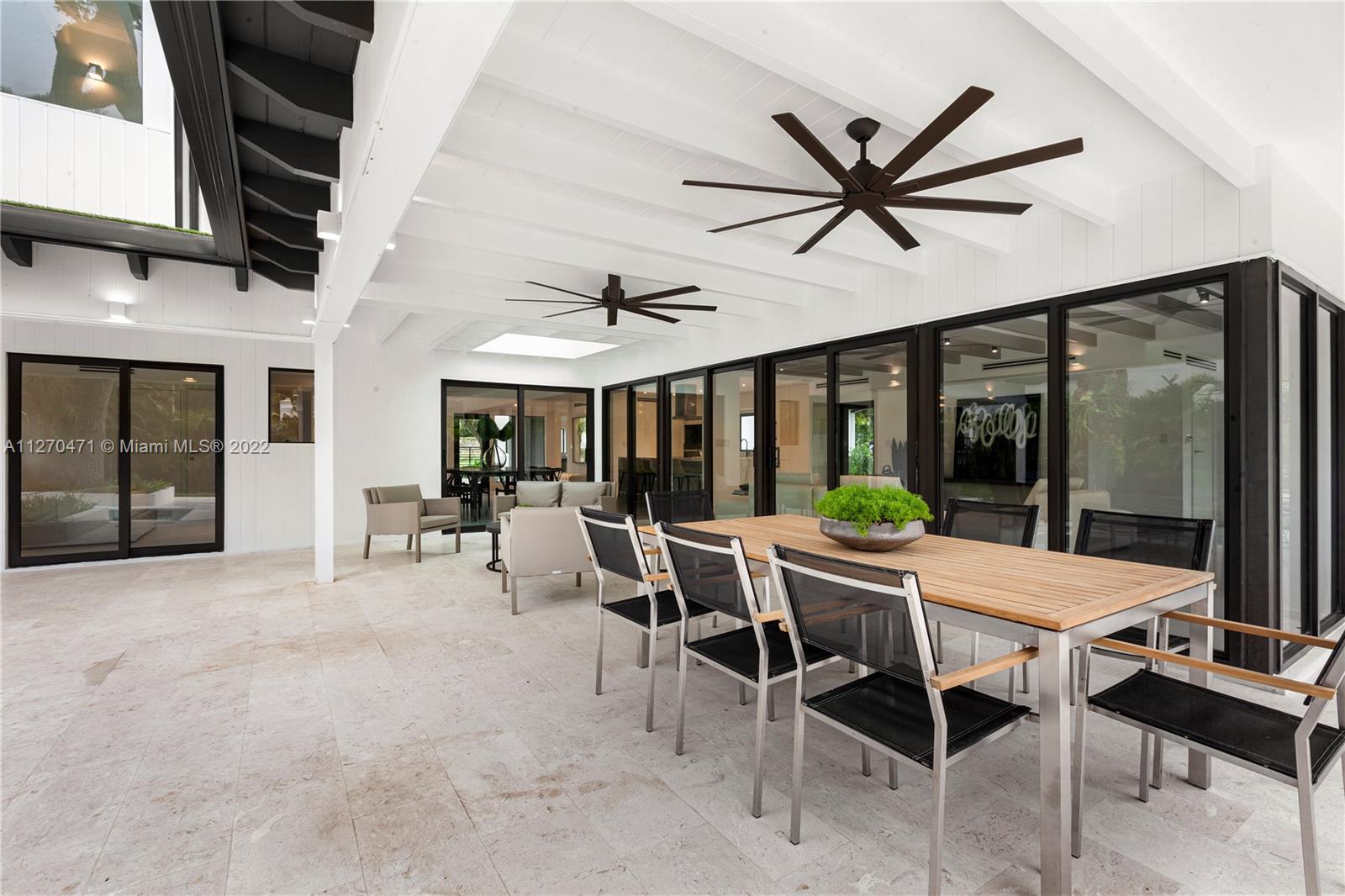 4095 Battersea Road Miami, FL 33133 - Photo 36 of 40 a dining room with furniture a chandelier and a large window