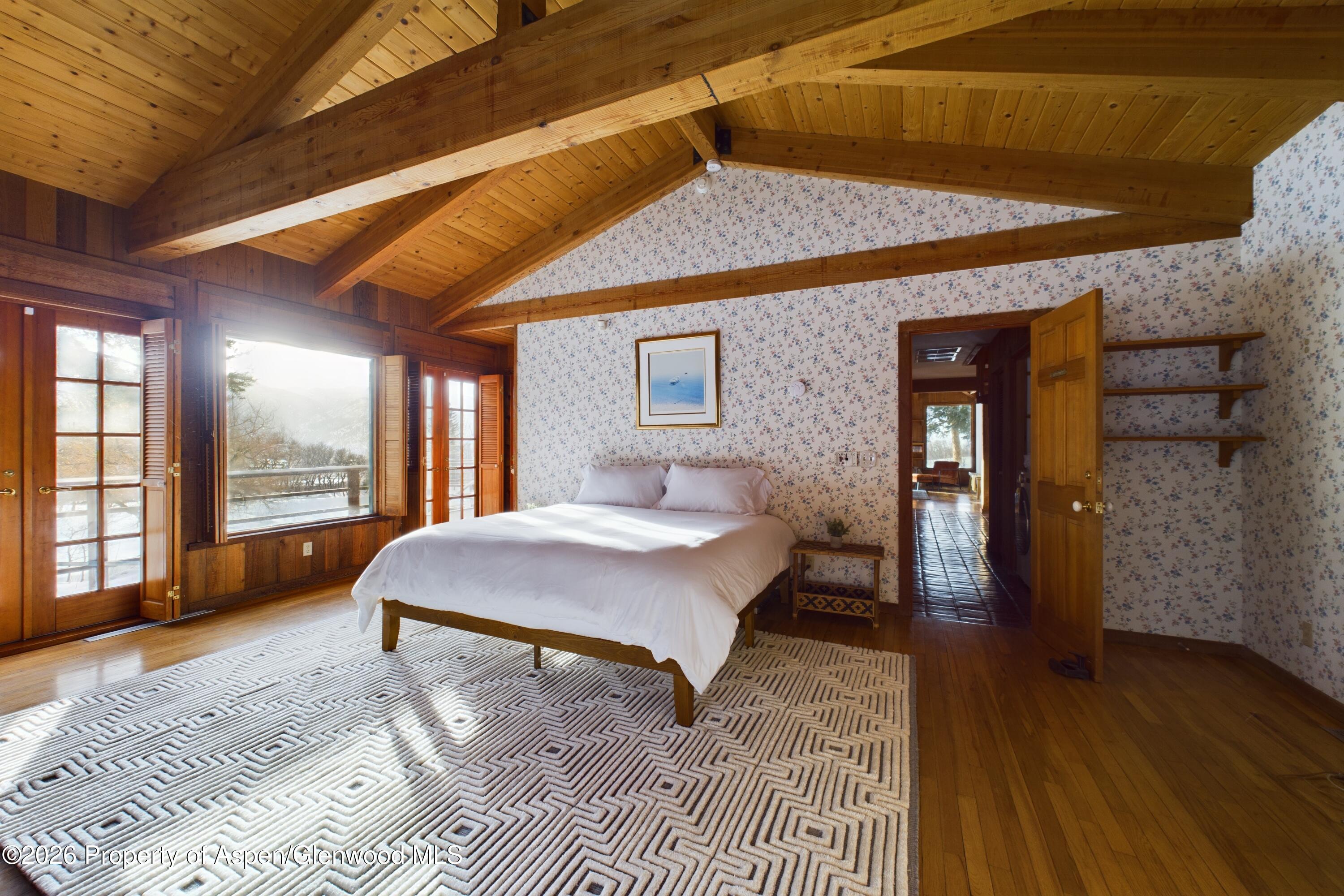 209 East Reds Road Aspen, CO 81612 - Photo 34 of 54 a spacious bedroom with a bed a dresser and wooden floor