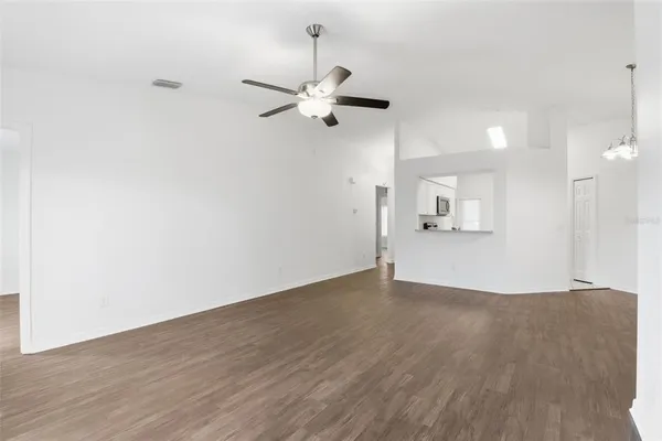 an empty room with wooden floor fan and windows