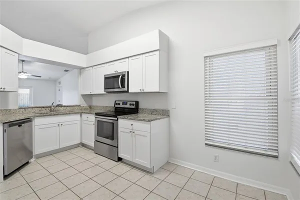 a kitchen with granite countertop white cabinets and stainless steel appliances