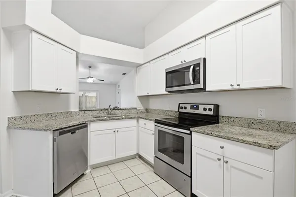 a kitchen with granite countertop white cabinets stainless steel appliances and a sink
