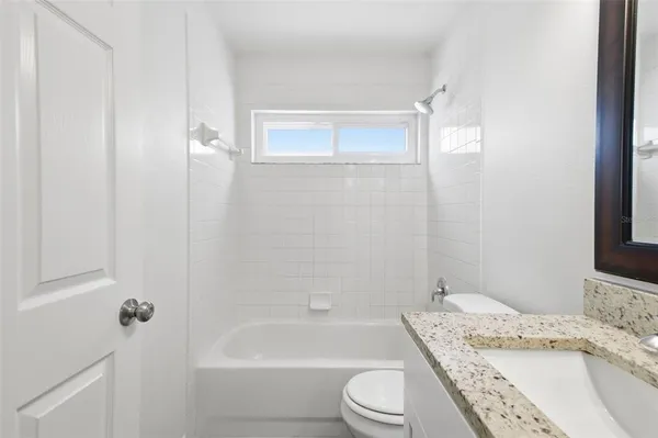 a bathroom with a granite countertop sink a toilet and bathtub