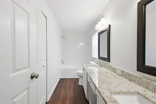 a bathroom with a granite countertop sink a mirror and a bathtub