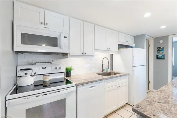 a kitchen with white cabinets and white appliances