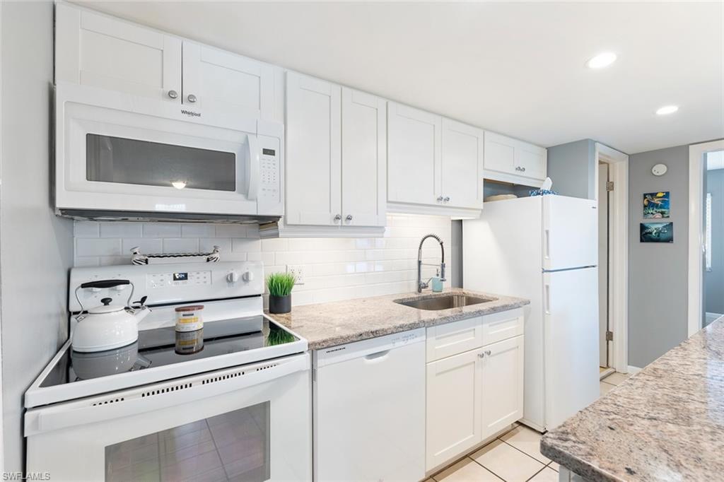 240 Palm Drive, Unit 481 Naples, FL 34112 - Photo 2 of 17 a kitchen with white cabinets and white appliances