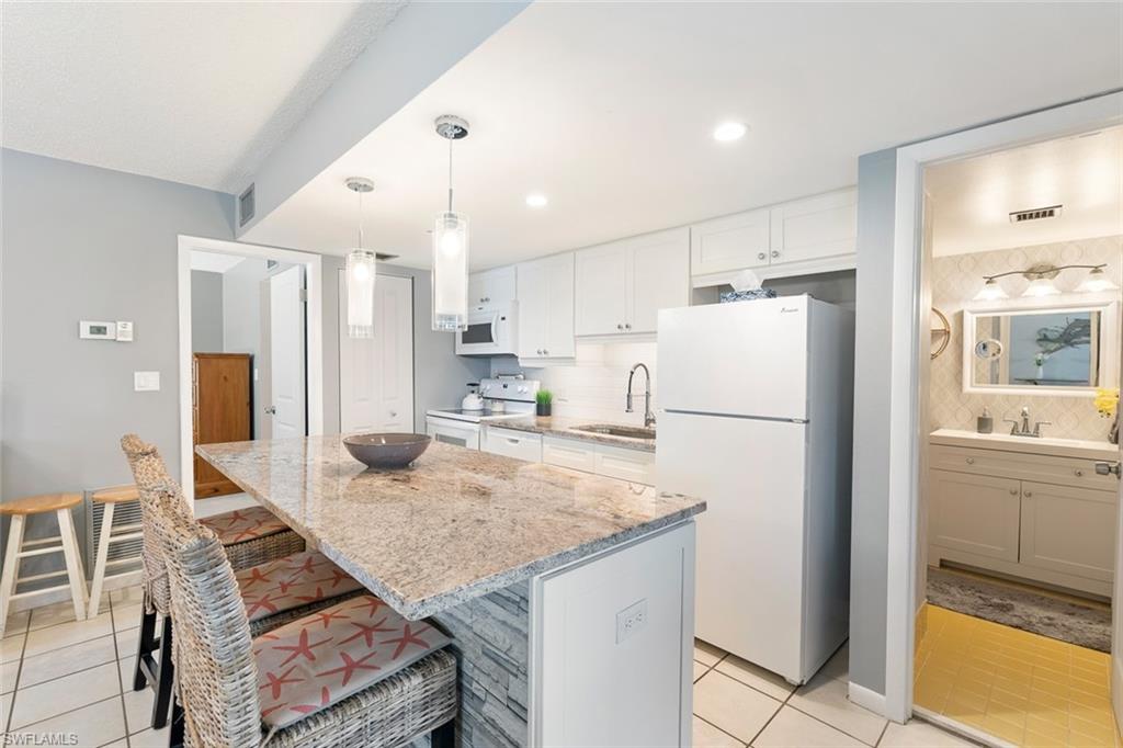 240 Palm Drive, Unit 481 Naples, FL 34112 - Photo 3 of 17 a kitchen with kitchen island a refrigerator a stove a sink and a counter space
