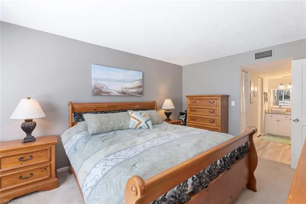 a bedroom with a bed and a lamp on dresser