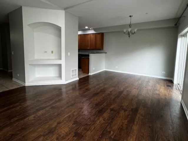 an empty room with wooden floor a flat screen tv and kitchen view