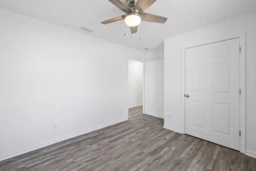 an empty room with wooden floor a ceiling fan and closet