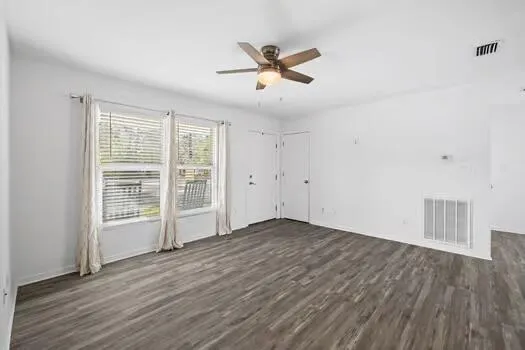 a view of an empty room with wooden floor and a window