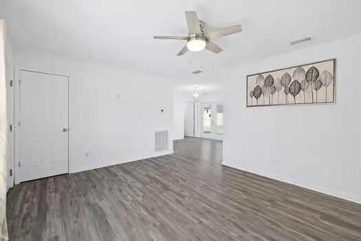 an empty room with wooden floor and ceiling fan