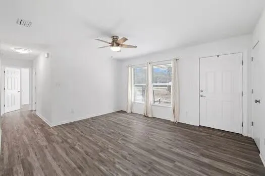 a view of empty room with wooden floor and ceiling fan