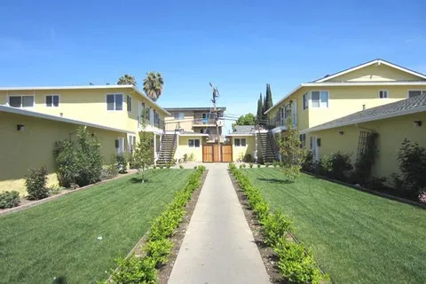 a view of a big house with a big yard and potted plants