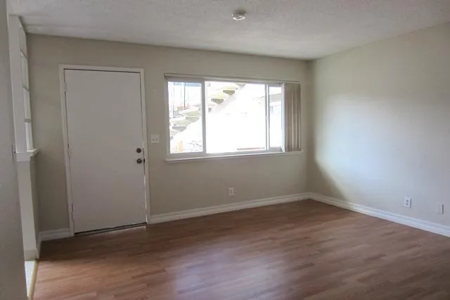 an empty room with wooden floor and windows