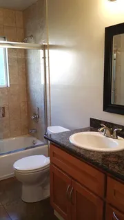 a bathroom with a granite countertop sink toilet a mirror and shower