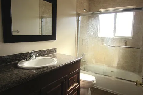 a bathroom with a sink a toilet a mirror and shower