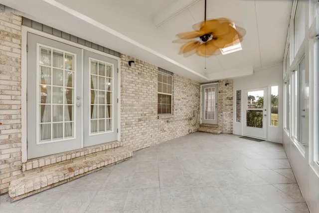 an empty room with chandelier fan and windows