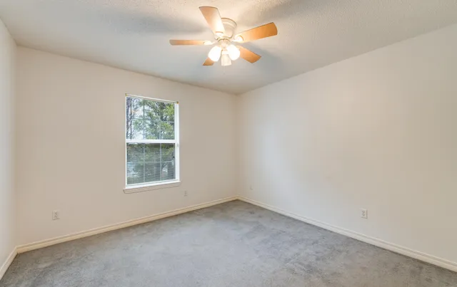 an empty room with a window and a fan