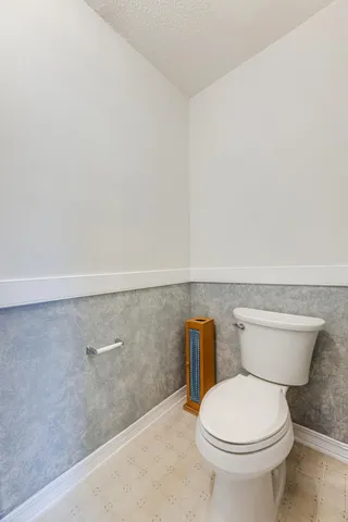 a white toilet sitting next to a white wall