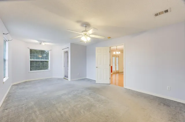 an empty room with windows and fan