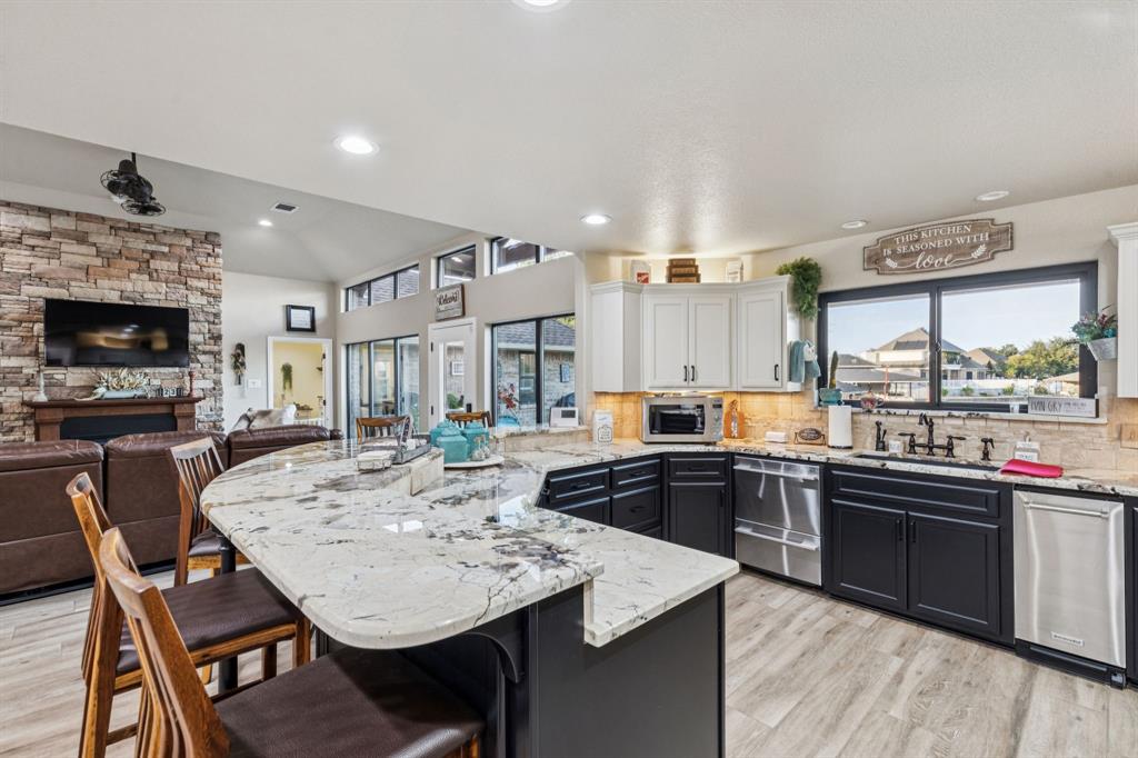 2325 River Road Granbury, TX 76048 - Photo 21 of 40 a kitchen with a stove a sink dishwasher a dining table and chairs with wooden floor