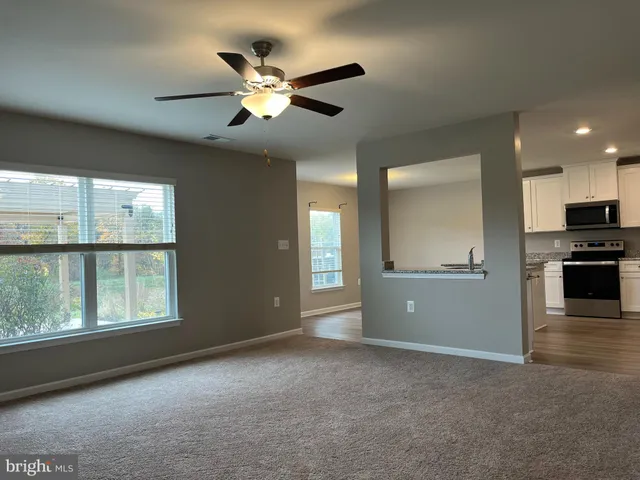 a view of an empty room with a window and kitchen view