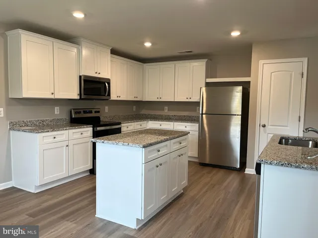 a kitchen with a refrigerator a stove top oven a sink and cabinets