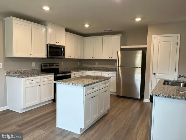 a kitchen with a refrigerator a stove top oven a sink and cabinets