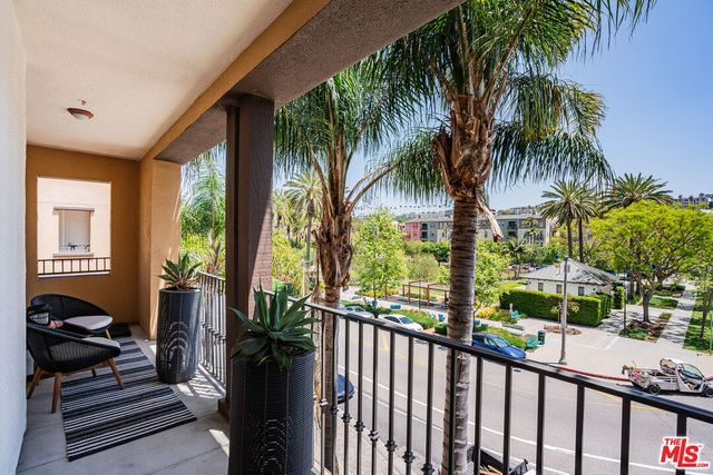 a view of a balcony with potted plants and palm trees