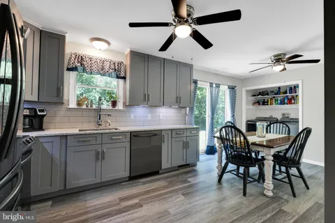 a kitchen with stainless steel appliances granite countertop a table chairs sink and wooden floor