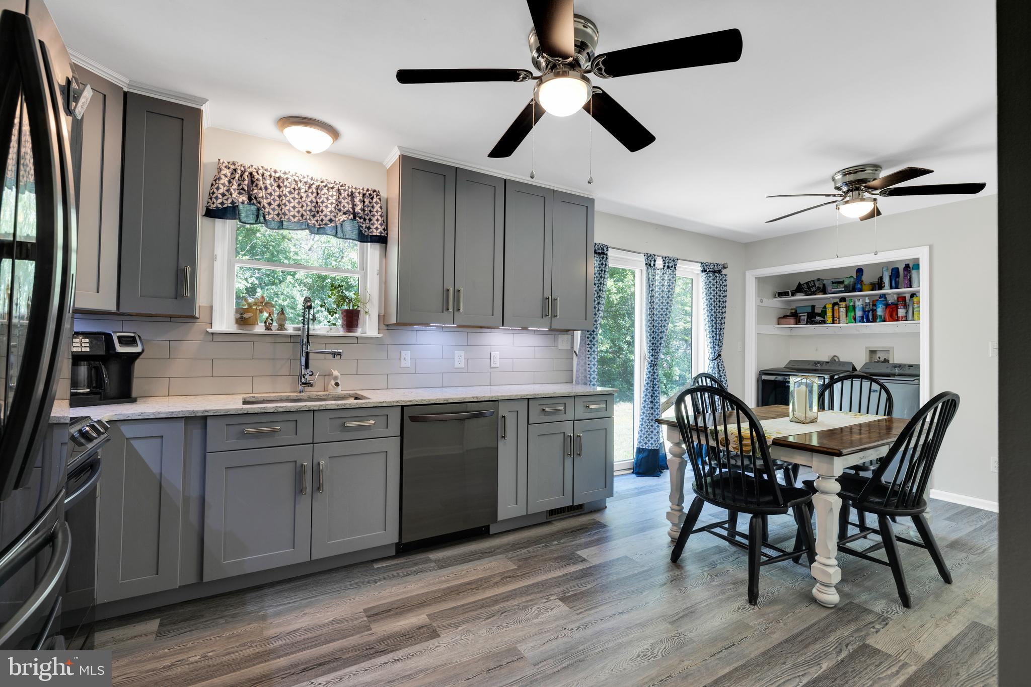 97 Bertolet Mill Road Oley, PA 19547 - Photo 8 of 35 a kitchen with stainless steel appliances granite countertop a table chairs sink and wooden floor