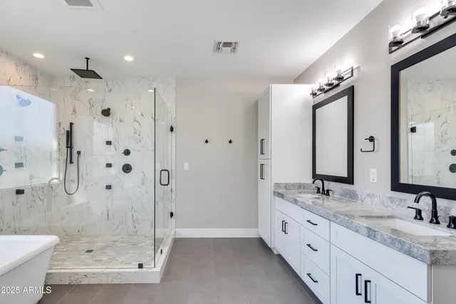 a bathroom with a granite countertop double vanity sink mirror double shower and a bathtub