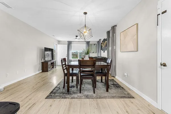 a dining room with furniture a chandelier and wooden floor