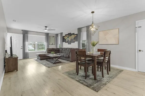 a dining room with wooden floor a chandelier a wooden table and chairs