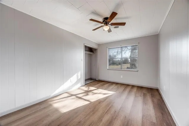 a view of empty room with wooden floor and fan
