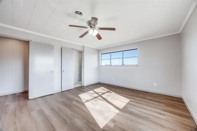 a view of empty room with wooden floor and fan