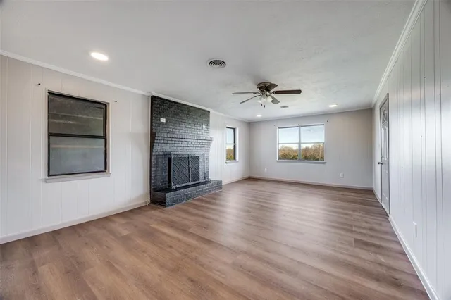 an empty room with wooden floor fireplace and windows